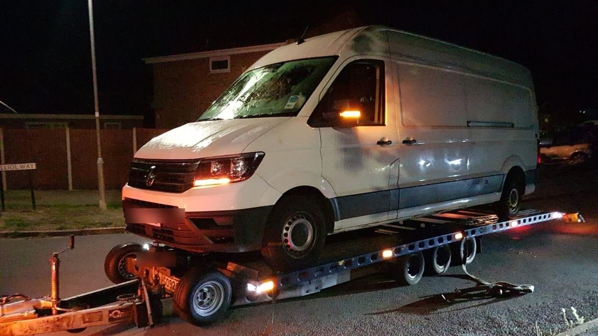 Van loaded on a flatbed recovery trailer during a night-time collection in Kent